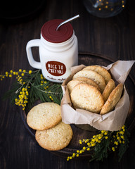 Homemade cookies with sesame seeds and pine nuts, decorated with mimosa flowers. Wooden background