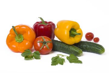 Red yellow and orange peppers with tomatoes on a white background..Cucumbers with colorful peppers in composition on a white background.