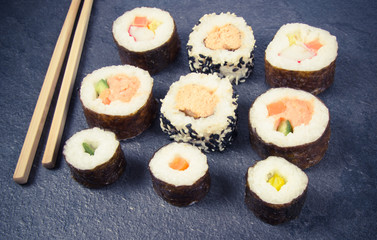 Various kinds of sushi on the dark background.