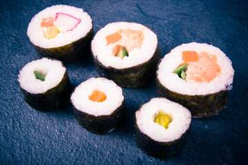 Various kinds of sushi on the dark background.