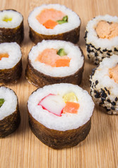 Various kinds of sushi on the wooden background.