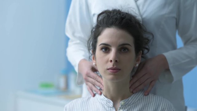 Doctor examining a patient and checking her neck