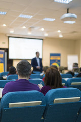 Conferences and Business Meetings Concepts. Mature Experienced Male Presenter Giving a Talk in Front of the Group Of Listeneres During a Conference.