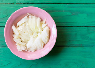 Chopped onion on a plate on a green wooden background.