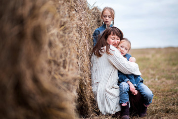 family - mother and two daughters are resting near the hay