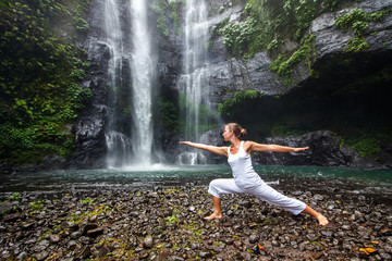 Woman practices yoga near Sekumpul waterfall in Bali, Indonesia