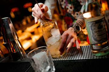 Bartender mixing cocktails at the bar dark background