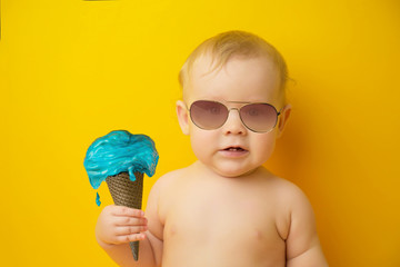 cute baby girl in sunglasses with dripping ice cream  blue color on yellow background.  concept of...