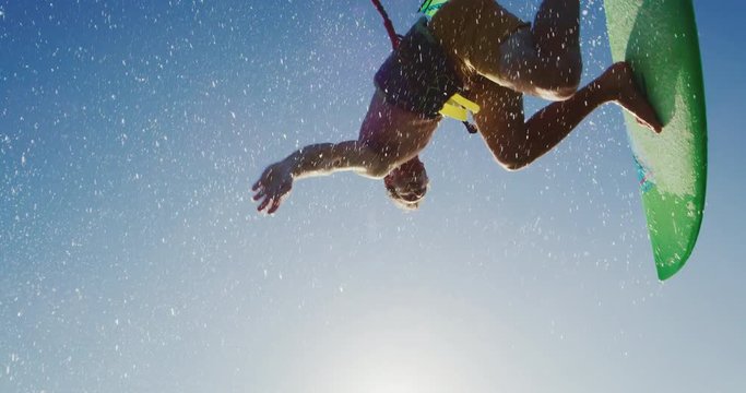 Kitesurfing at sunset in slow motion, kiteboarder gets big air