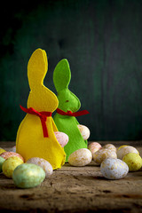 Handmade easter rabbits and eggs on wooden table. 
