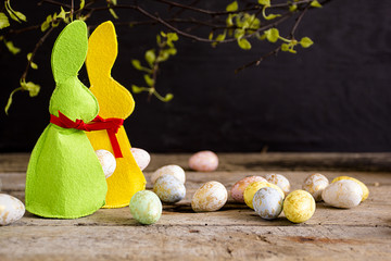 Easter rabbits and eggs on wooden table. Dark background. Copy space. 