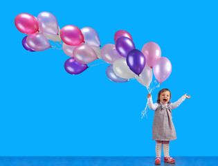 Happy laughing little girl with balloons .