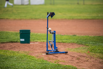 Youth baseball mechanical pitching machine set up on the infield mound to practice batting.