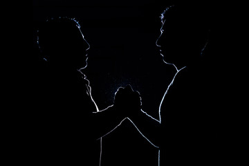 Silhouette of two brothers, who squeeze each other hands, symbolizing friendship
