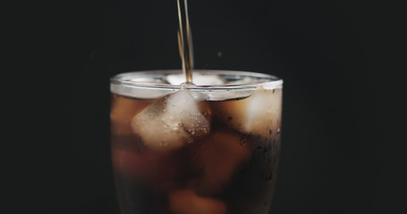 closeup cola pouring into glass with ice
