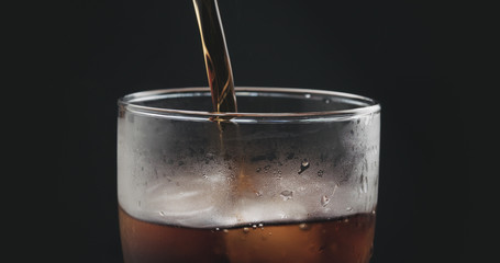 closeup cola pouring into glass with ice