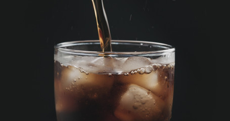 closeup cola pouring into glass with ice