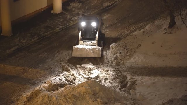 Night Snow loading by road machinery after heavy snowfall in residential block,