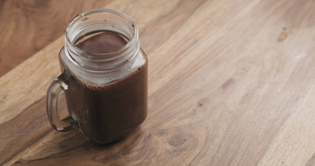 cocoa drink in glass jar with handle on wood table