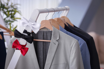 Hangers with suits and bow ties on rack in tailor's workshop