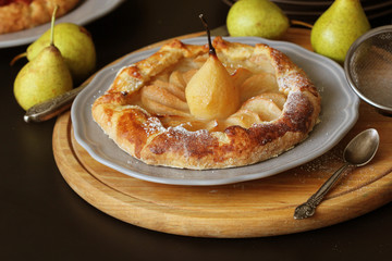 Homemade galette with pears on black background. French cuisine - Breton galette. Sweet open pie