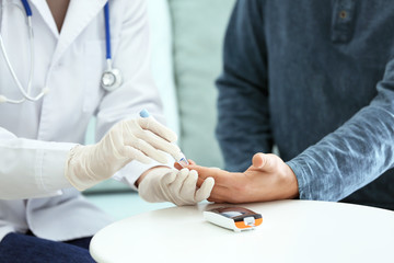 Doctor taking sample of diabetic patient's blood using lancet pen, closeup - obrazy, fototapety, plakaty