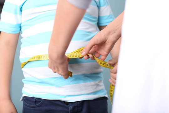 Doctor Measuring Overweight Boy In Clinic