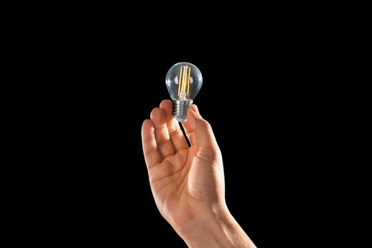 Man holding light bulb on black background. Lamp changing