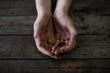 Poor woman with coins on wooden background