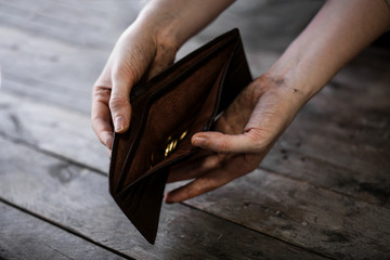 Poor woman holding purse with coins on wooden background