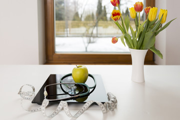 Healthy lifestyle, dieting and nutrition concept. Geen apple on scales next to the measuring tape...
