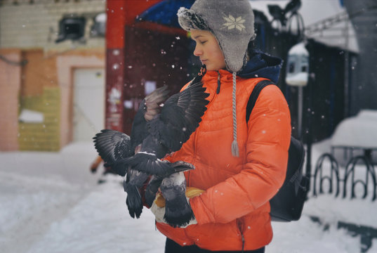 A girl feeds pigeons in winter