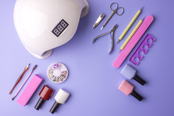 Set of cosmetic tools for manicure and pedicure on a purple background. Gel polishes, nail files and clippers, top view