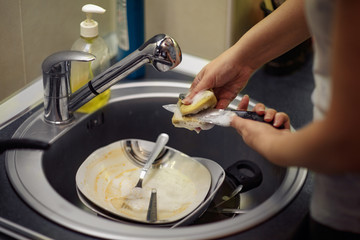 wash the dishes in the kitchen - Female hand with sponge washing dish.