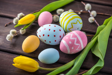 Fototapeta na wymiar Colorful Easter eggs with yellow Tulip hand painted on a dark wooden background. Holiday spring card