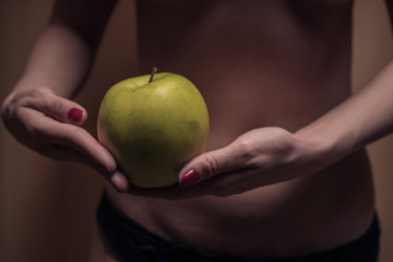 The concept of diet. Sexy female waist and an apple against the background of a woman's body. Healthy lifestyle