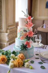 Home wedding for-tiered cake on the table in the restaurant decorated with pink roses and green leaves in a rustic style