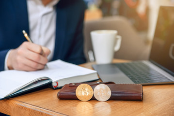 Businessman works in his workplace with notebook, laptop and makes a business plan. Cryptocurrency mining. Golden and silver bitcoin coin. Selective focus.