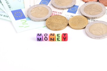 verschiedene euros auf einem haufen und davor bunte kleine würfel mit buchstaben die das wort money bilden