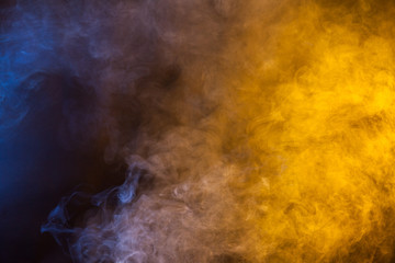Blue and yellow smoke on a dark background. Texture and desktop picture
