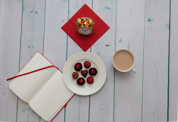 Sweets on a plate, coffee and a diary on the table
