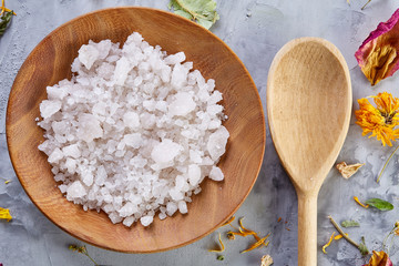 Composition of spa treatment on white background. Sea salt and flowers background, close up, top view, selective focus.