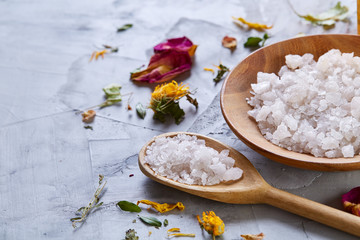Composition of spa treatment on white background. Sea salt and flowers background, close up, top view, selective focus.