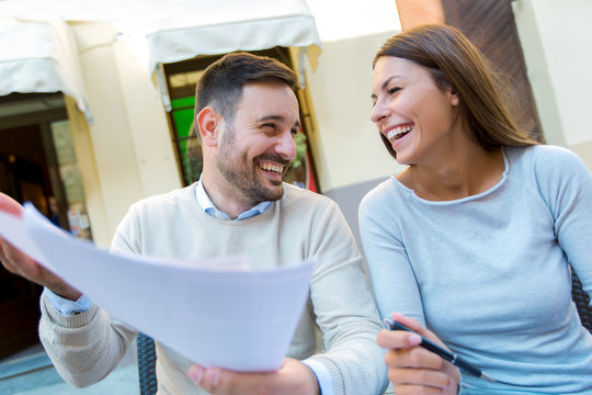 Young couple sitting in a cafe enjoying in coffee and conversation viewing documents