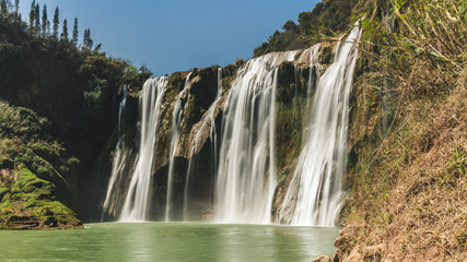 Fototapeta premium Waterfalls, Jiulong Waterfalls closeup with morning sky on background at Luoping County Town, China.