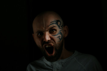 tattoo on the face,  male portrait in the form of an assassin, cosplay,  tattooed brutal man,  guy with a tattooed face