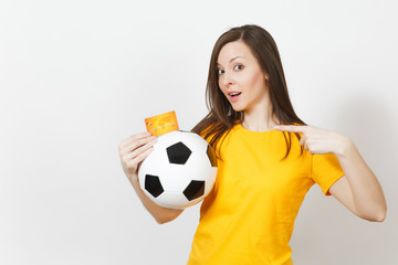 Beautiful European young cheerful woman, football fan or player in yellow uniform holding credit card soccer ball isolated on white background. Sport, play football game, excitement lifestyle concept.