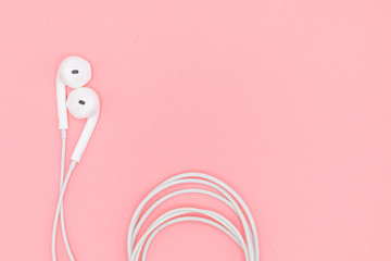 Top view Lovely Closeup of White Earphones on Pink Pastel plastic texture background. Pastel color concept, Minimal concept. Copy space. Music is my life concept. Valentine concept