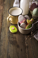 Plate with colourful Easter cookies and glass of milk, rustic style