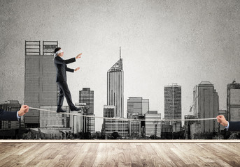 Business concept of risk support and assistance with man balancing on rope